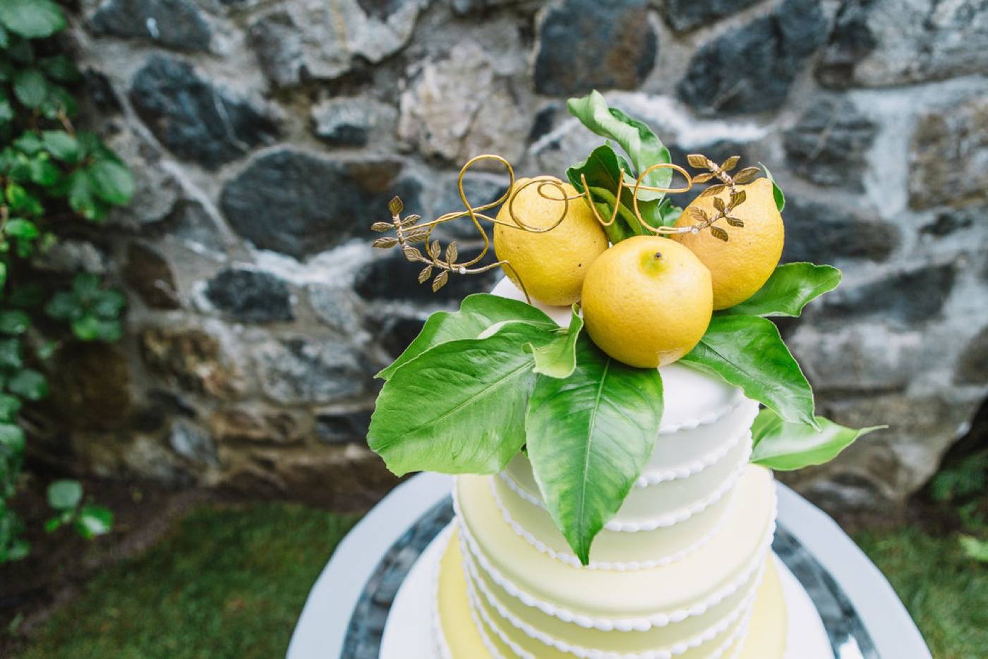 Gâteau à trois étages avec un glaçage dégradé jaune et surmonté de citron frais pour une fête d'anniversaire de mariage