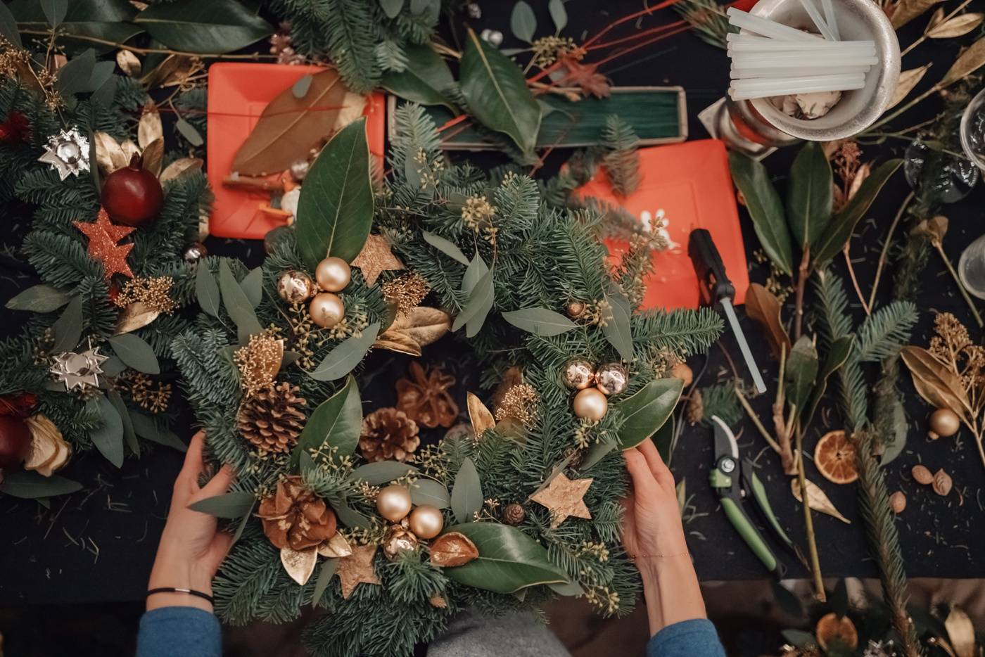 Couronne de pin avec oranges séchées et cloches d'or confectionnée lors d'un atelier de couronnes de Noël