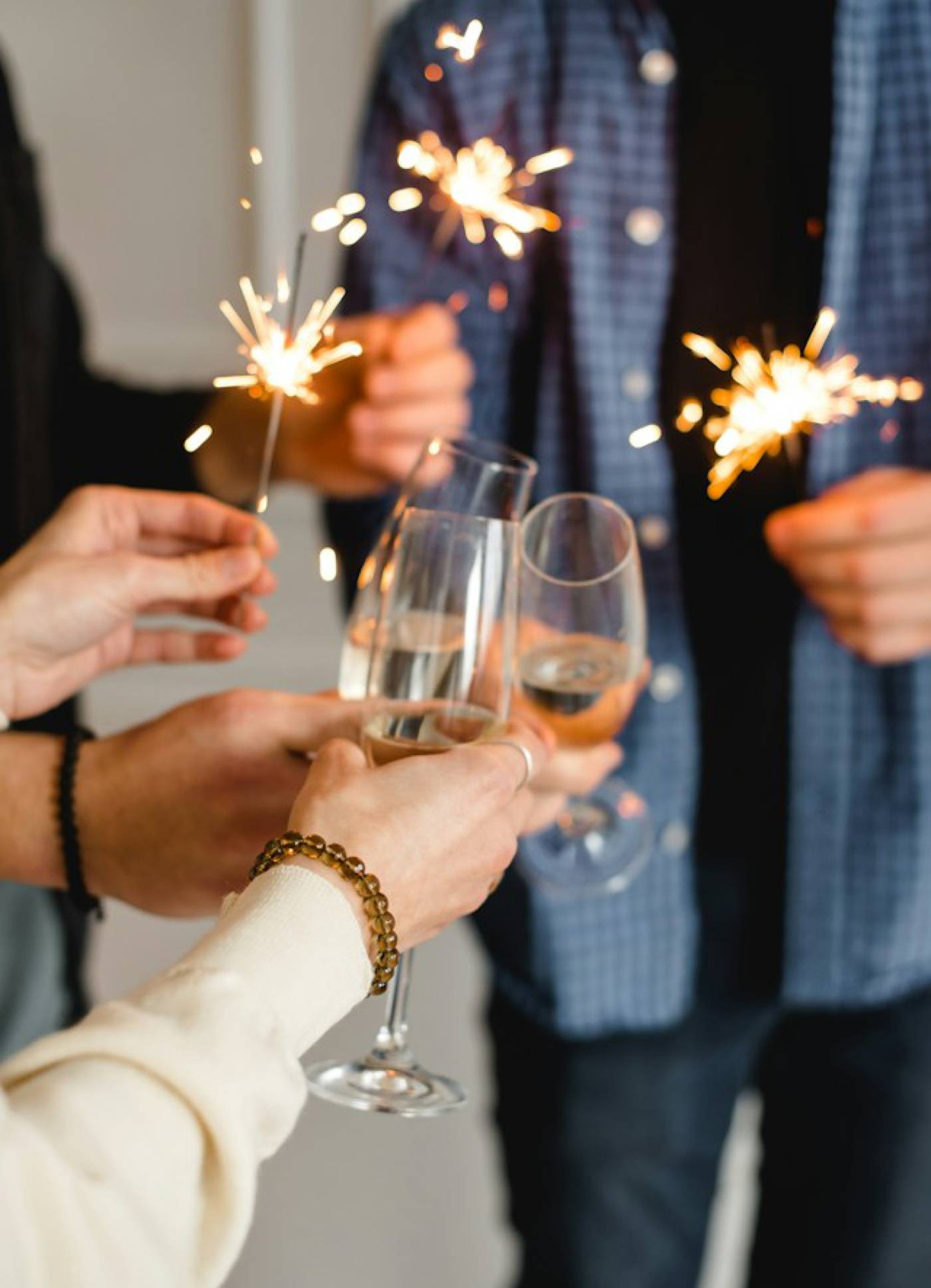 Group of friends holding sparklers and toasting with glasses of champagne at an end-of-year party